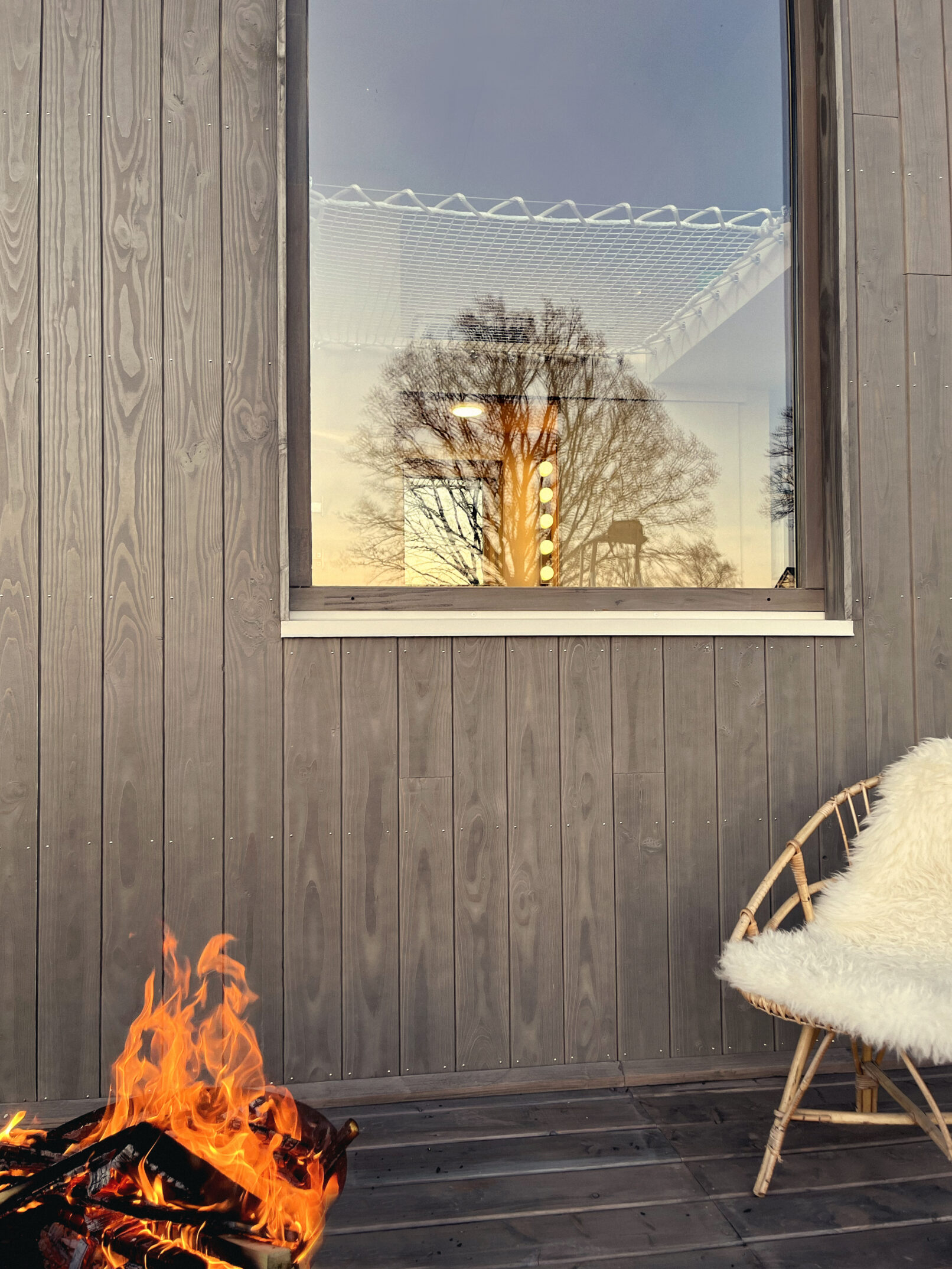 Une terrasse avec un fauteuil et un feu de camps pour montrer l'activité relaxante pouvant avoir lieu dans la tiny house.